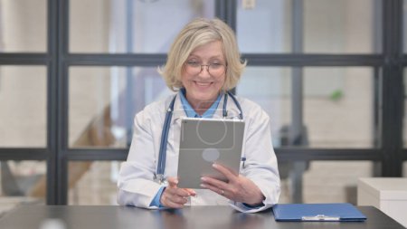 Téléchargez les photos : Chat vidéo en ligne par Old Female Doctor sur tablette - en image libre de droit