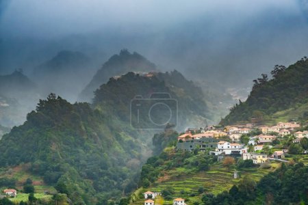 Traditionelles Terrassendorf Sao Vicente, Insel Madeira, Portugal. Kleine Häuser und Gärten inmitten einer grünen Berglandschaft bei stürmischem Wetter.