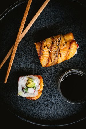 Foto de Rollo de sushi de plátano con cangrejo en plato azul, fotografía de sushi delicioso y salsa de soja y palillos - Imagen libre de derechos