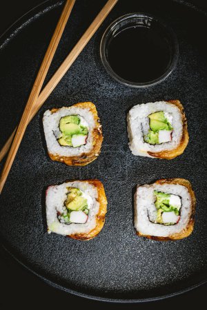 Foto de Cuatro rollos de sushi en plato azul, fotografía de sushi delicioso y salsa de soja - Imagen libre de derechos