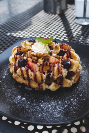 Photo for A waffle with fruit and whipped cream on a black plate - Royalty Free Image