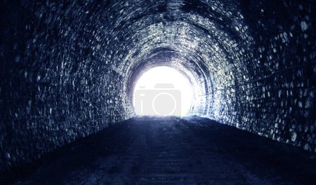 Helles Tageslicht am Ende eines alten steinernen dunklen Tunnels, das Konzept, in eine andere Welt zu gehen.