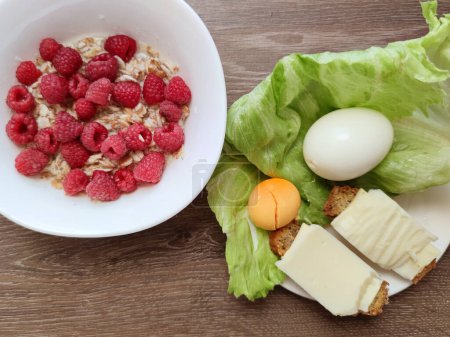 oatmeal with raspberries and eggs with cheese and lettuce, healthy nutrition.