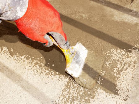 une main de travailleur applique une solution d'étanchéité à un sol en béton avec une brosse, dispositif d'étanchéité.