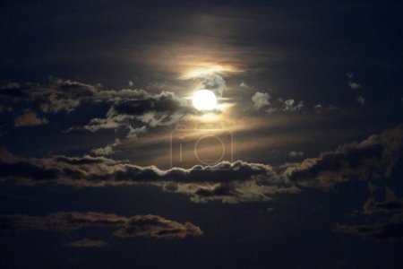 heller Mond hinter den Wolken am dunklen Nachthimmel.