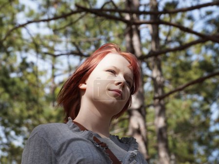 Porträt eines rothaarigen Teenagers im Wald, Ansicht von unten.
