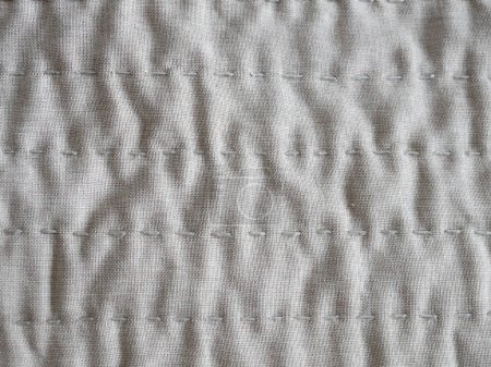 textured beige fabric with detailed stitching and embroidery for a natural textile background