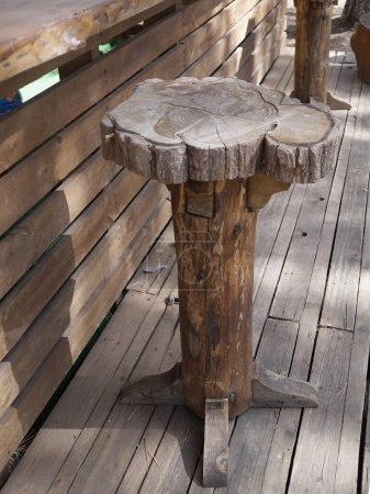 rustic handcrafted wooden bar stool on outdoor terrace.