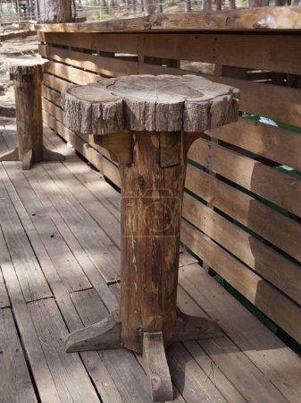 tabourets de bar en bois à une longue table en planches faite à la main sur une terrasse ouverte.