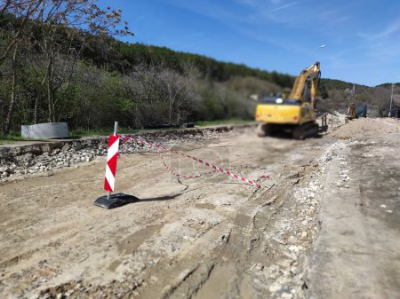 sitio de construcción de carreteras con excavadora y barreras de seguridad.