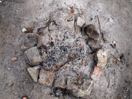 Überreste eines von Steinen umgebenen Lagerfeuers im Freien.