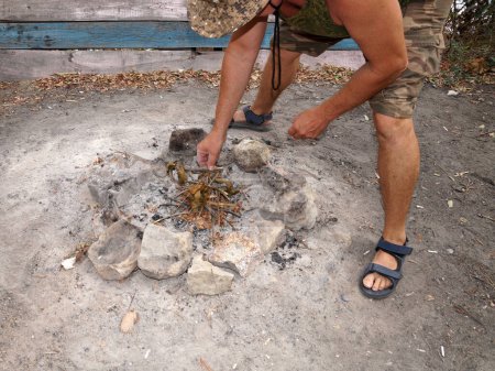Foto de Hombre preparando fogata con piedras y ramitas al aire libre. - Imagen libre de derechos
