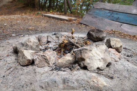 Überreste eines von Steinen umgebenen Lagerfeuers im Freien.