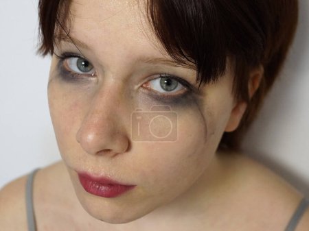 close-up portrait of a tear-stained teenage girl with mascara smeared eyes.