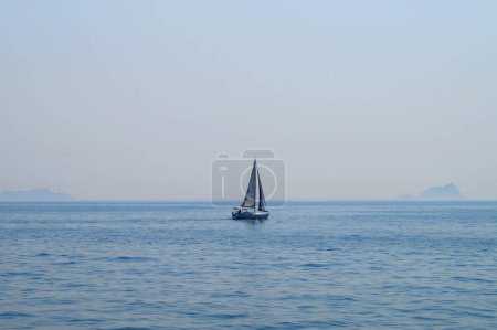 petit voilier en mer sur fond d'horizon marin.