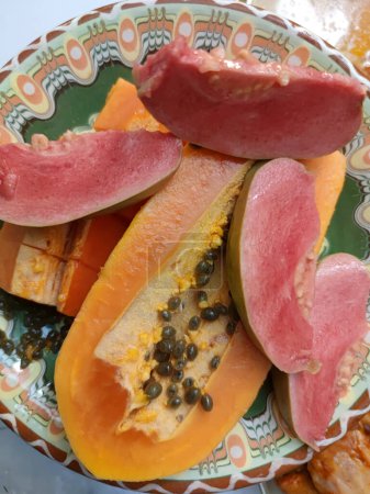 sliced papaya and guava on a patterned ceramic plate.