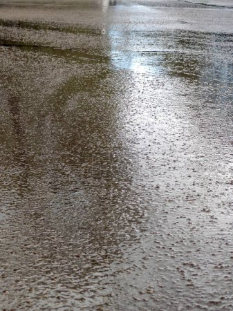 superficie de asfalto húmedo que refleja la luz después de la lluvia.