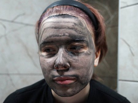 Porträt eines Mädchens mit Kohlegesichtsmaske in Nahaufnahme.