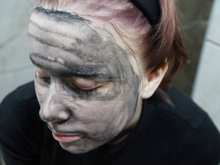 visage d'une adolescente avec un masque de boue nettoyante gros plan