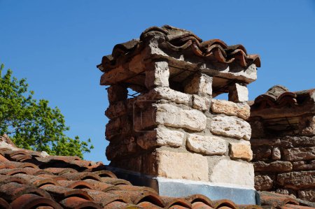 brick chimney on a tiled roof close-up.