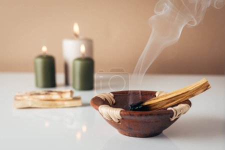 Photo for Palo santo burning stick and candles in background with copyspace - Royalty Free Image