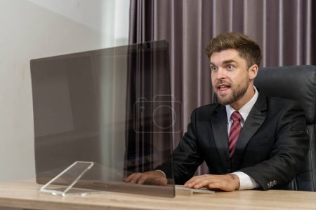 Photo for A successful businessman smiles with satisfaction after seeing results on a monitor. The businessman is confident and in control, and he is clearly enjoying his success. - Royalty Free Image