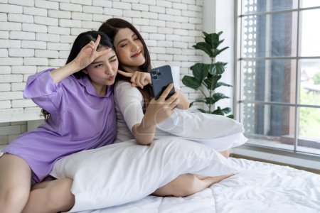 Photo for Memories before bedtime Young woman couple in bed Take a selfie with your phone Capture images through the lens of your smartphone. To create a collection of delightful shared moments. - Royalty Free Image