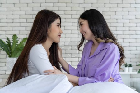 Photo for Attractive lesbian couple sharing an intimate hug while sitting on bed in bedroom, captures romantic moment between female lgbtq+ partners enjoying affectionate morning cuddle. - Royalty Free Image