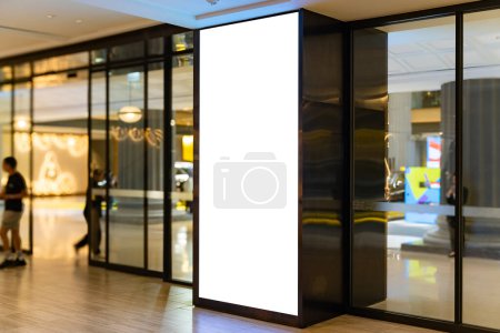 Simular pantalla led vertical en blanco con iluminación cerca de la puerta de entrada de vidrio, Espacio vacío para la publicidad, Promoción en posición prominente, atraer la atención en el pasillo en el centro comercial. personas borrosas