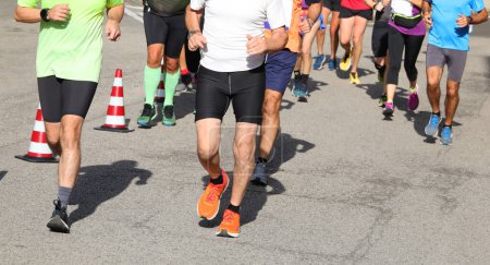 Foto de Corredores atléticos con piernas musculosas durante la carrera a pie en las calles de la ciudad - Imagen libre de derechos