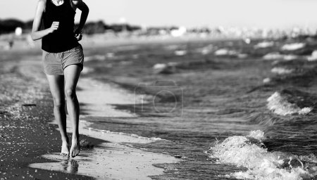 Photo for Girl jogging running on the seashore in summer with black and white effect - Royalty Free Image