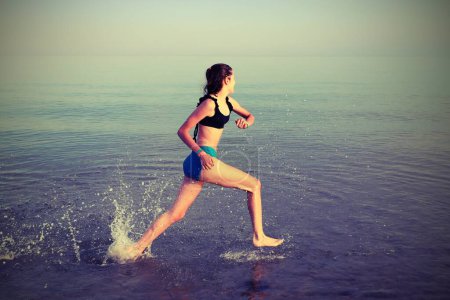 Téléchargez les photos : Jeune fille dirige la formation par la mer avec effet tonique vieux en été - en image libre de droit