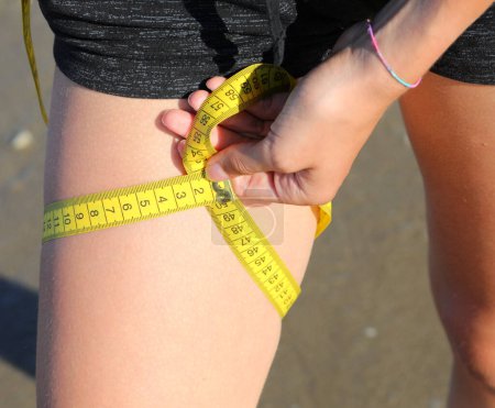Photo for Measurement of the circumference of the leg of girl with  tape measure and measures in centimeters - Royalty Free Image