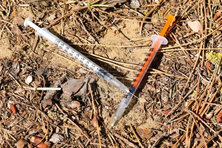 Téléchargez les photos : Deux seringues abandonnées utilisées par des toxicomanes dans un parc public - en image libre de droit