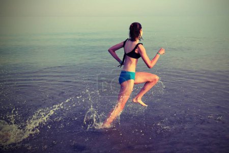 Téléchargez les photos : Young girl runs on the sea water during training with antique effect tones - en image libre de droit