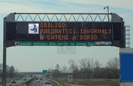 Téléchargez les photos : Signal large sur l'autoroute avec texte obligeant l'équipement d'hiver et contrôle de vitesse en langue italienne - en image libre de droit