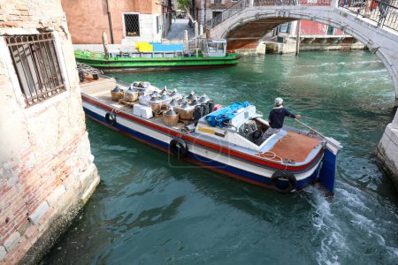 Photo for Boat for the transport of wine demijohns in the canal in venice in italy - Royalty Free Image