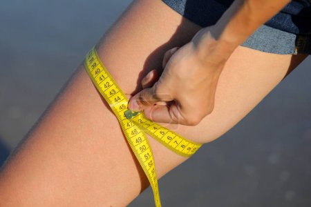 Photo for Girl measuring her thighs with the yellow flexible tape measure - Royalty Free Image