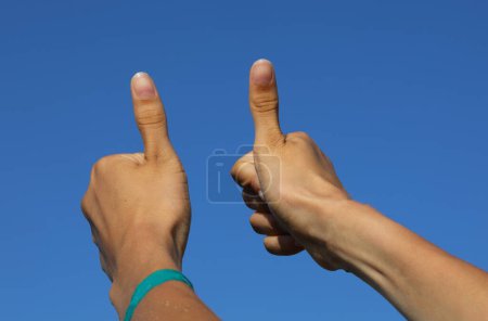 Téléchargez les photos : Deux pouces vers le haut des mains du jeune homme qui indiquent le succès et la positivité - en image libre de droit