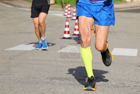 Foto de Anciano corredor con la piel del muslo que vibra durante la carrera en la ciudad en las calles - Imagen libre de derechos
