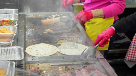 Photo for Cook during the preparation of the takeaway food cooked on a hot plate during the village festival - Royalty Free Image