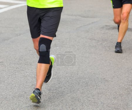 runner with kneegiera runs during the running race in the paved road in the city