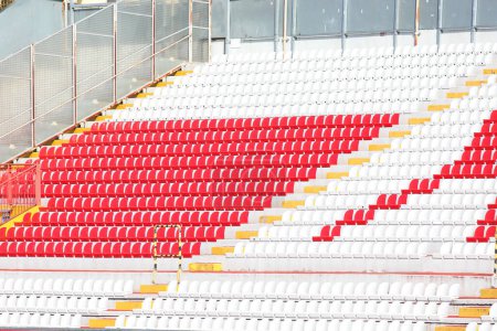 Photo for Many empty red and white seats in the stadium stands without people before the match - Royalty Free Image