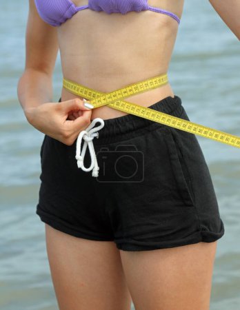 Foto de Joven chica delgada midiendo su cintura con metro amarillo - Imagen libre de derechos