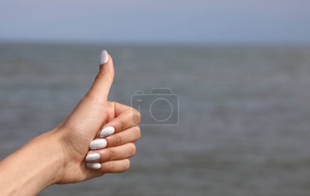Foto de Mano de chica joven con los pulgares hacia arriba por el mar - Imagen libre de derechos