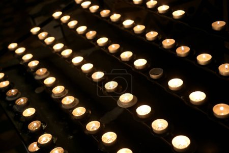 Photo for Lit votive candles with the flame by pilgrims during the religious service inside the church of god - Royalty Free Image