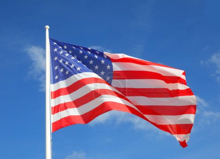 Téléchargez les photos : Drapeau américain brillant avec des rayures rouges et blanches et des étoiles agitant dans le ciel bleu - en image libre de droit