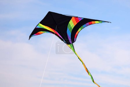 Foto de Cometa multicolor con inserciones negras volando libremente en el cielo azul - Imagen libre de derechos