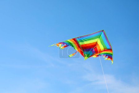 Foto de Cometa multicolor con cola larga y colorida volando libre en el cielo azul - Imagen libre de derechos