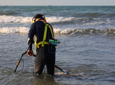 Foto de Recuperándose con un detector de metales en busca de joyas y monedas perdidas en el mar por los bañistas - Imagen libre de derechos